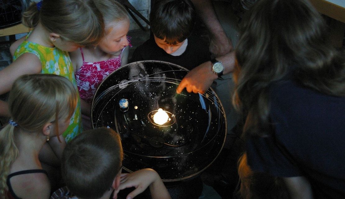 Kinder sehen sich ein Model des Sonnensystems an
